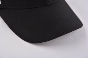 the curved brim of the black and white baseball hat at right side KN2012232
